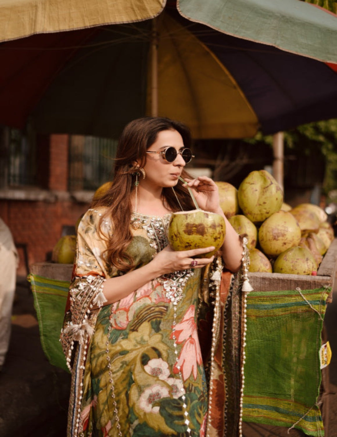 Woman holding a coconut amidst coconuts and umbrellas in an outdoor setting